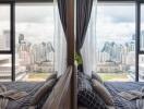 Modern bedroom with a panoramic city view through floor-to-ceiling windows