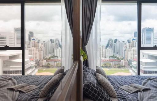 Modern bedroom with a panoramic city view through floor-to-ceiling windows