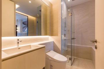 Modern bathroom with well-lit vanity, spacious shower area, and beige tiles