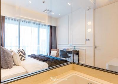 Modern bedroom with large bed and workspace, ample lighting, and mirror wardrobe