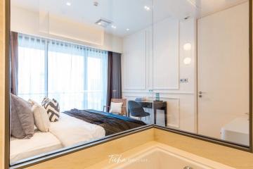 Modern bedroom with large bed and workspace, ample lighting, and mirror wardrobe