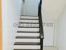 Modern staircase with wooden steps and black handrail in a residential home