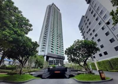 Modern high-rise residential building with lush greenery in the foreground