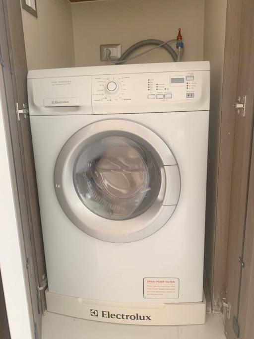 Modern white Electrolux washing machine in a compact laundry area within a home