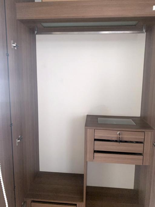 Compact bedroom corner showing a built-in wardrobe with an open drawer and empty shelves