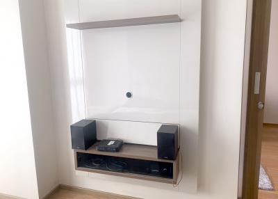 Minimalist living room media wall with mounted shelf and electronic devices