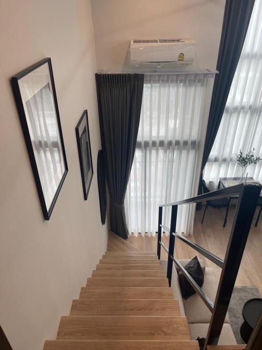 Elegant wooden staircase with white walls and framed pictures leading to the upper level of a home