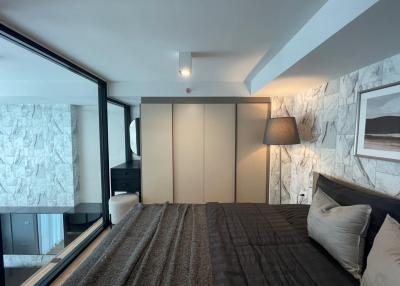 Modern bedroom with large bed, marble accent wall, and ample natural light