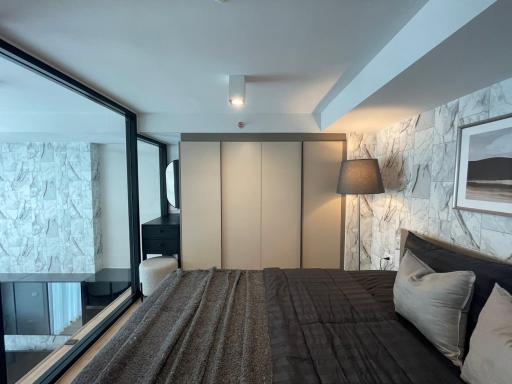 Modern bedroom with large bed, marble accent wall, and ample natural light