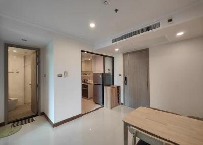 Compact modern apartment interior view showing the kitchen, entry door, and a glimpse of the bathroom