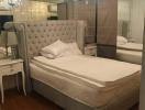 Elegant bedroom with large tufted headboard and mirrored wardrobe