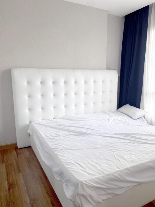 Spacious bedroom with a large white tufted headboard and hardwood floors