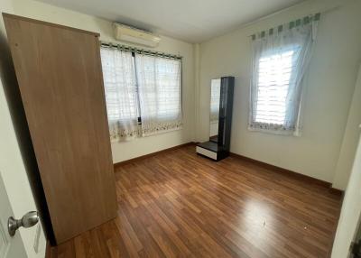 Spacious bedroom with wooden flooring and air-conditioning unit