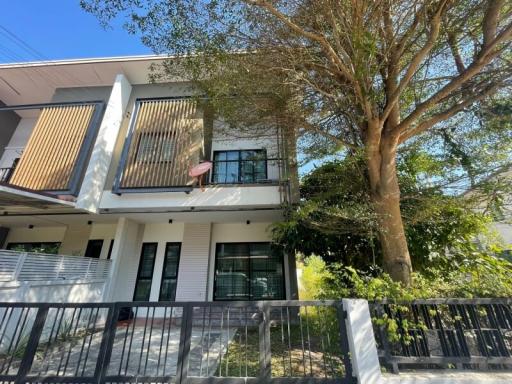 Modern two-story house with a balcony and front yard tree