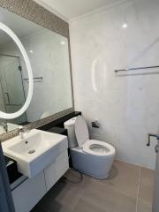 Modern tiled bathroom with round mirror and glass shower