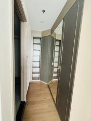 Modern hallway interior with wooden floor and open door revealing a built-in wardrobe