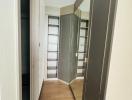 Modern hallway interior with wooden floor and open door revealing a built-in wardrobe