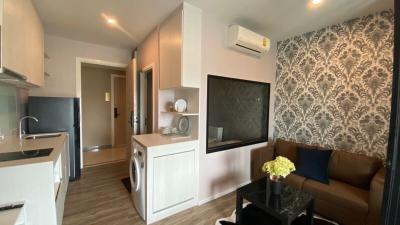 Compact living area with kitchenette, sofa, and entertainment unit