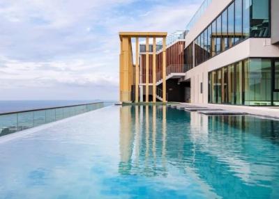 Modern infinity pool with ocean view next to a luxurious building