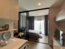 Modern apartment interior with open plan living space including a kitchen area and a glimpse into the bedroom