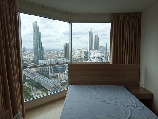 Modern bedroom with large windows offering a city view