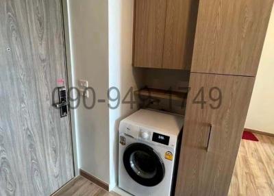 Compact laundry area with washing machine and wooden cabinets