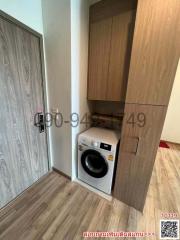 Compact laundry area with washing machine and wooden cabinets