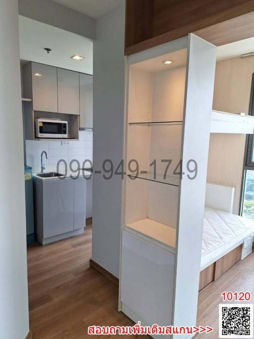 Compact modern kitchen with adjacent living space featuring built-in shelves and appliances