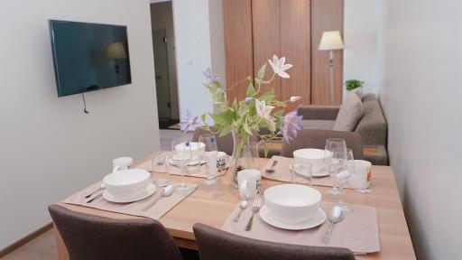 Modern dining area with table set for a meal and open plan living space in the background