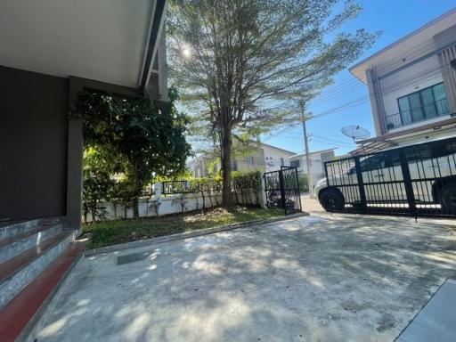 Spacious driveway with gated entrance and lush tree in a residential property