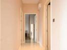 Narrow hallway in a residential home with light walls and tiled flooring