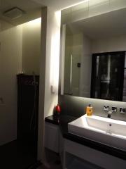 Modern bathroom with sleek design featuring a walk-in shower, large mirror, and contemporary sink