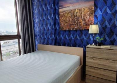 Cozy bedroom with blue geometric pattern wallpaper and cityscape artwork