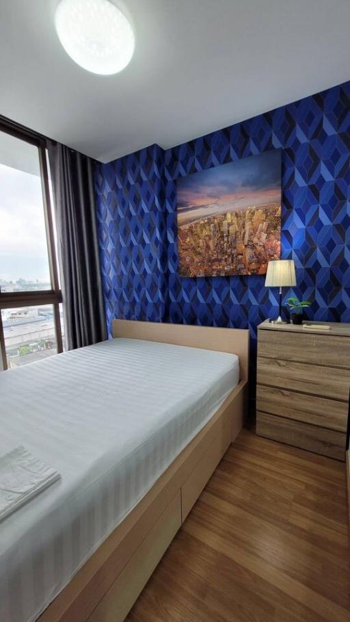 Cozy bedroom with blue geometric pattern wallpaper and cityscape artwork