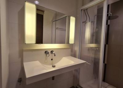 Modern bathroom interior with wall-mounted sink, mirror, and shower area