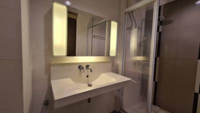 Modern bathroom interior with wall-mounted sink, mirror, and shower area