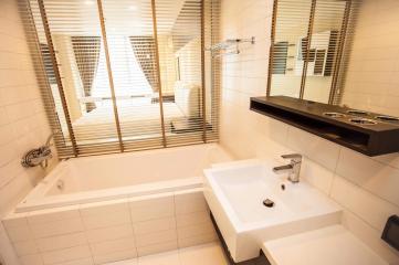 Spacious modern bathroom with a bathtub, double sink, and large window blinds