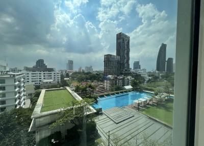 Panoramic city view with clear skies, swimming pool, and green areas from an apartment window