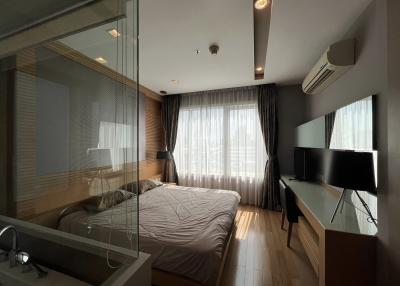 Modern bedroom with large bed, glass partition, and mounted television