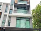 Modern multi-story residential building facade with balconies and a car parked in front