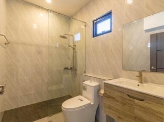 Modern bathroom interior with glass shower, wall-mounted toilet, and sink