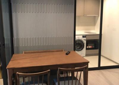 Modern dining area with wooden table, chairs, and adjacent laundry appliances