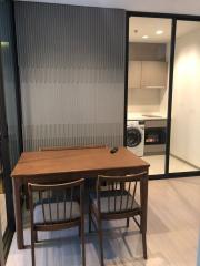 Modern dining area with wooden table, chairs, and adjacent laundry appliances