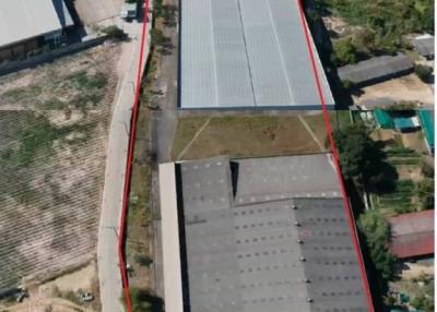 Aerial view of a large industrial property with adjacent plot of land and a lake
