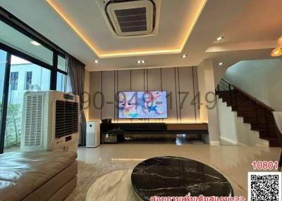 Modern living room with LED lighting, large screen TV, and staircase