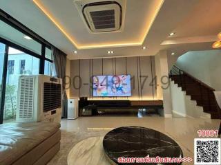 Modern living room with LED lighting, large screen TV, and staircase