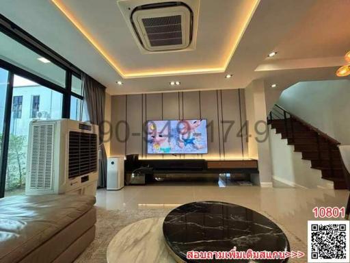 Modern living room with LED lighting, large screen TV, and staircase