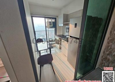 Compact apartment interior with open door showing kitchen and balcony