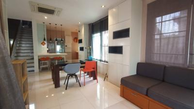 Well-lit living room with dining area and open staircase