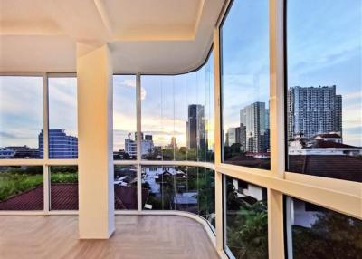 Spacious and bright open-concept living space with floor-to-ceiling windows overlooking the cityscape at sunset